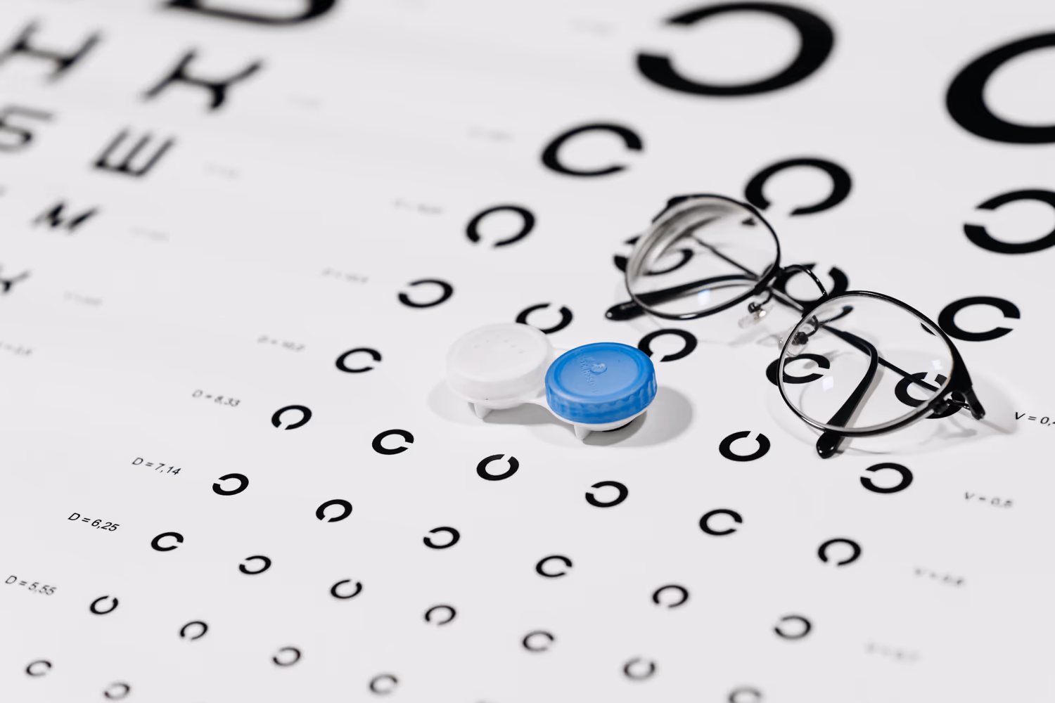 Estojo de lentes de contato e óculos sobre uma tabela de visão