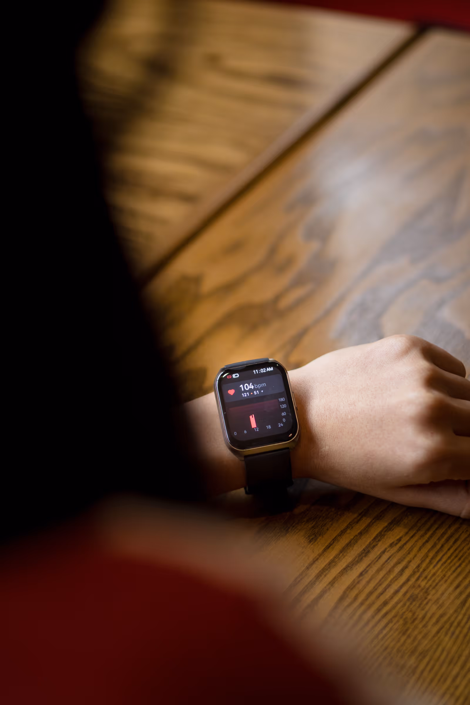 Pessoa olhando para o smartwatch no pulso exibindo frequência cardíaca de 104 bpm