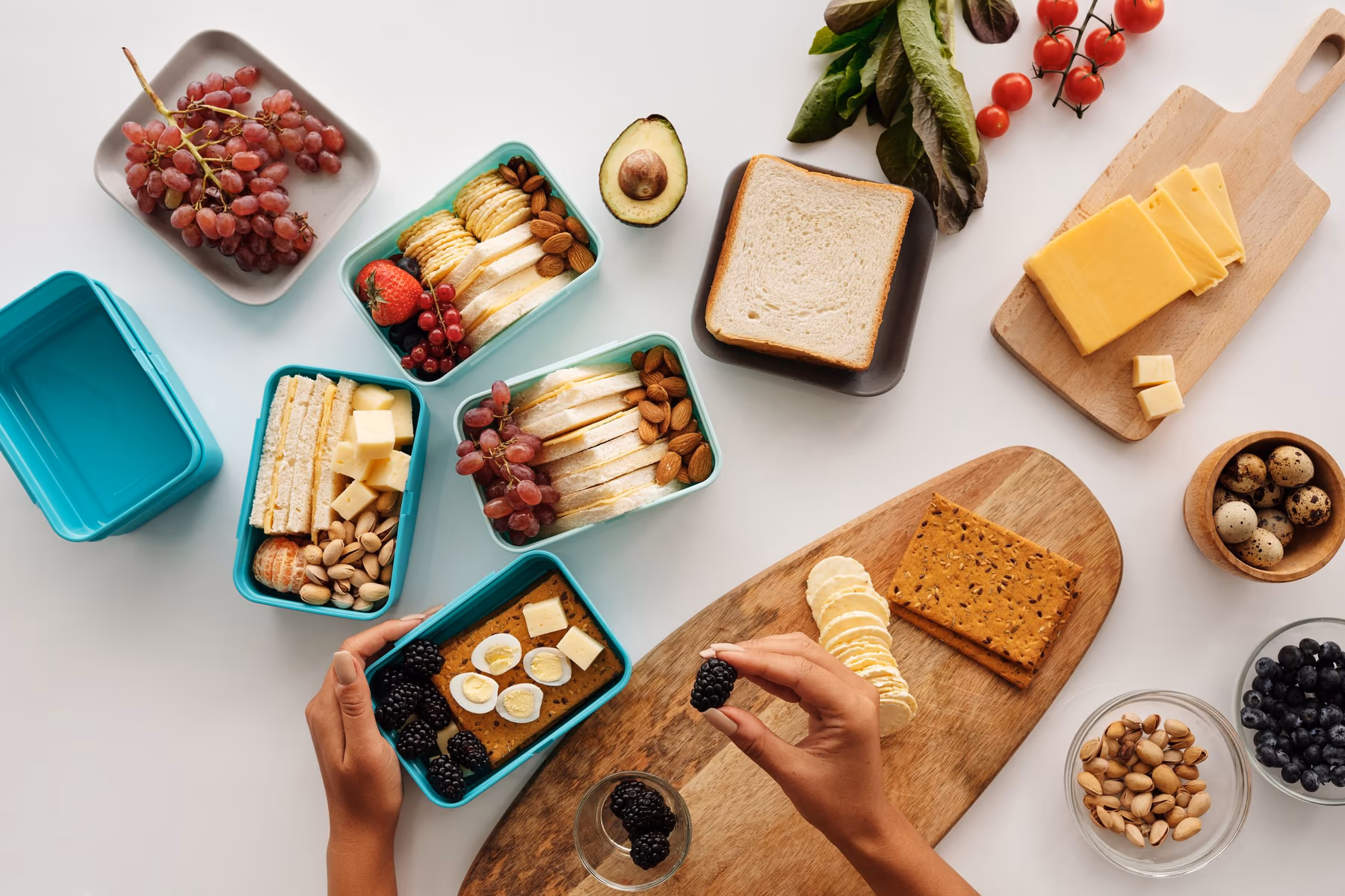 Pessoa organiza frutas, sanduíches, ovos e castanhas em recipientes de refeição