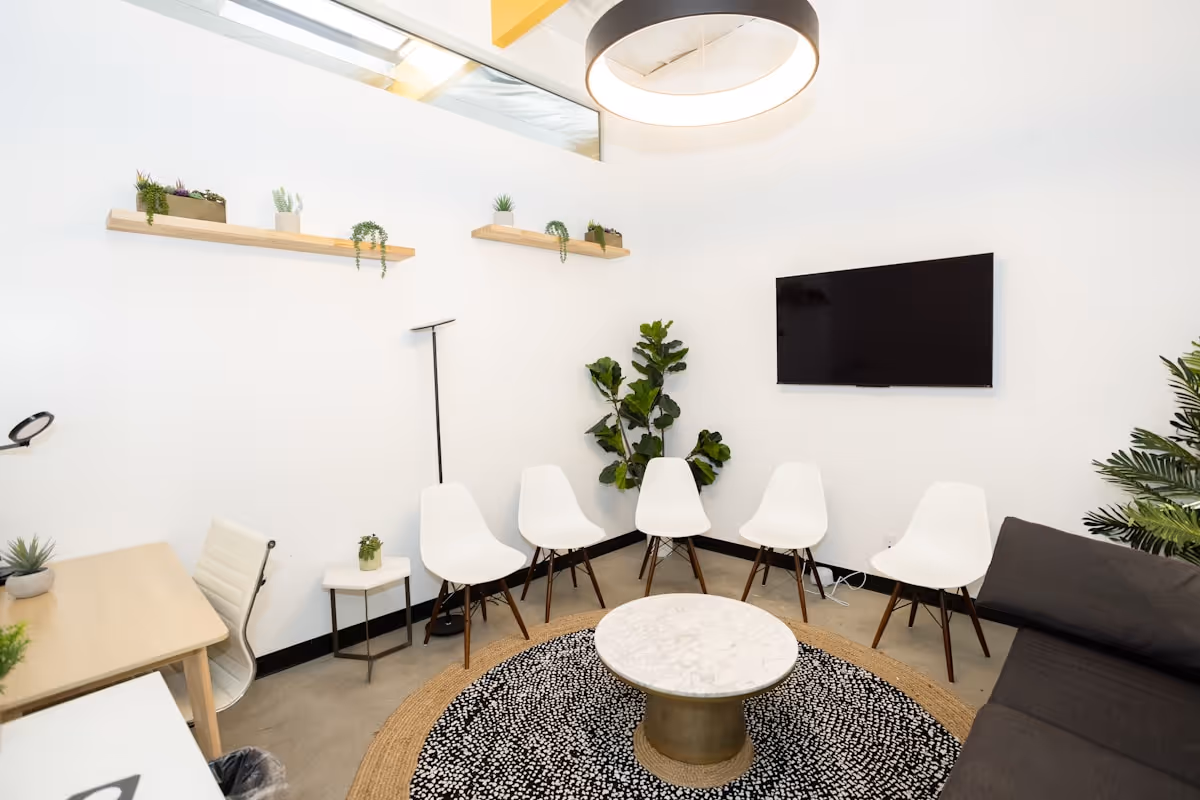 Sala de espera moderna com cadeiras brancas e plantas, ambiente calmo e acolhedor