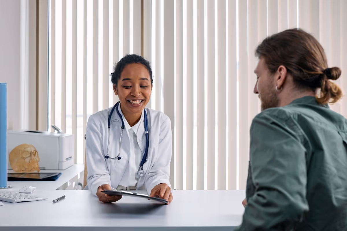 Médico e paciente adulto em conversa atenta durante consulta em clínica iluminada