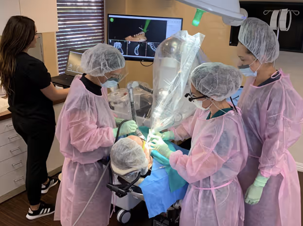 Robô Yomi da Neocis assistindo cirurgia de implante dentário com braço robótico sobre campo estéril