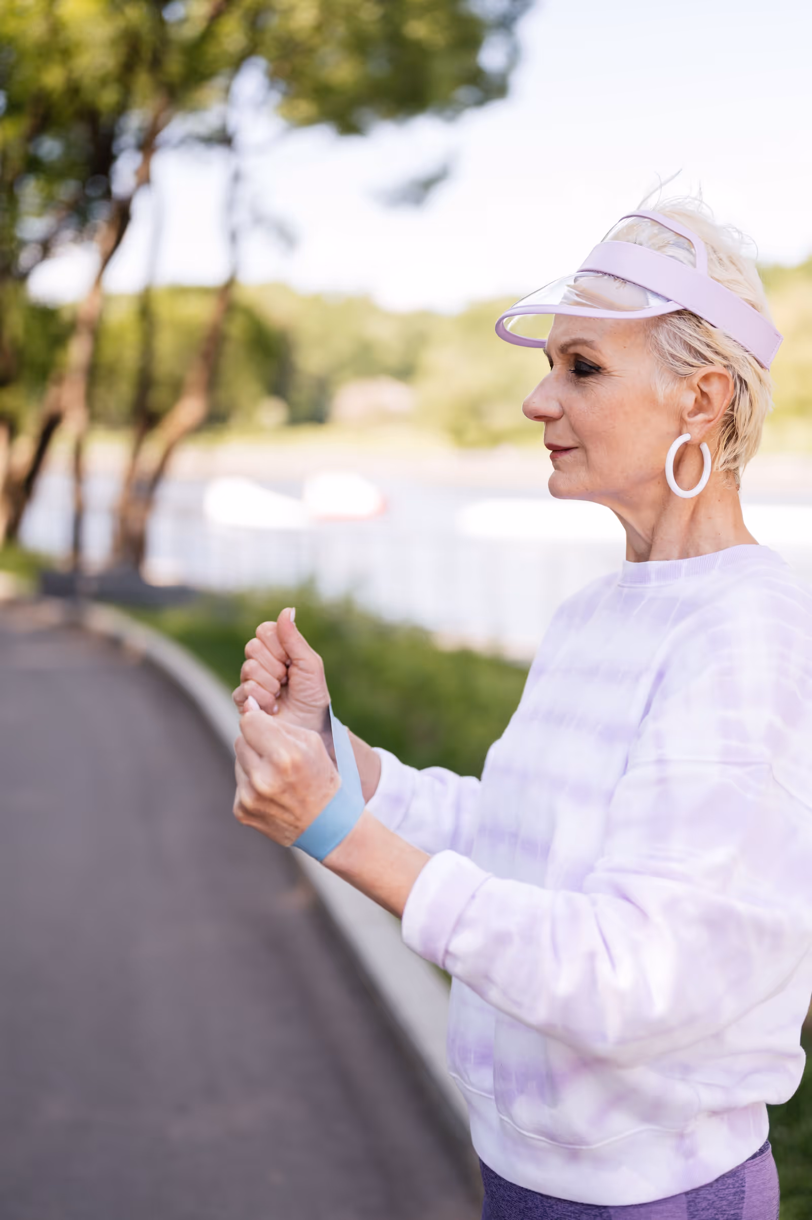 Mulher idosa treinando os braços com uma faixa elástica em um parque